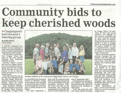 A newspaper clipping showing an image of a group of people in front of a wood