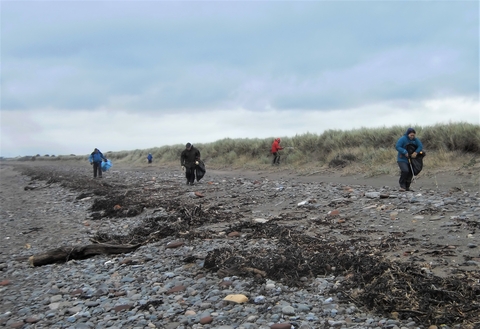 Four people take part in a litter-pick on a blustery beach