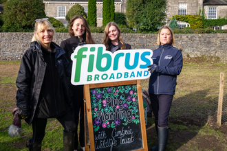 Four people holding up Fibrus broadband banner for collaboration with Cumbria Wildlife Trust 