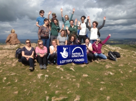 image of people on top of a hill holding Heritage lottery fund banner - Wild paths -copyright dorset wildlife trust