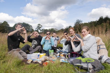 Group of people having a picnic outdoors making a heart shape with their hands - Katrina Martin 2020VISION