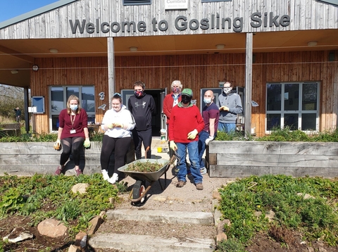 A group of volunteers standing in front of a building with 'Welcome to Gosling Sike written on it'