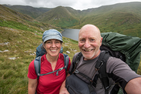 A man and a woman standing above a tarn in the fells