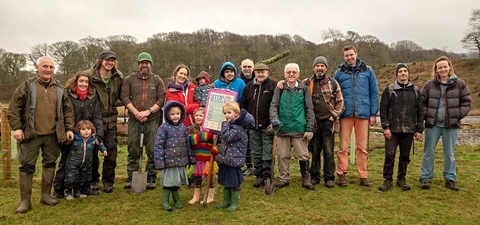 A group of people, from children to older people, standing in a line facing the camera