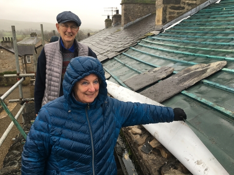 A man and a woman standing on scaffolding next to a roof