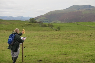 Artist at Eycott Hill Nature Reserve sketching and using viewfinders to frame Blencathra fell