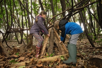 Image of boy and girl building den in woods © Adrian Clarke