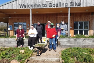 A group of volunteers standing in front of a building with 'Welcome to Gosling Sike written on it'