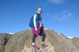 A young girl in hiking gear standing on a rock