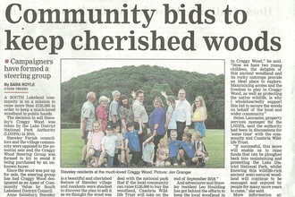 A newspaper clipping showing an image of a group of people in front of a wood