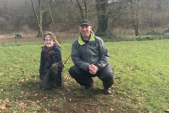 A man and his son posing in a field with trees behind