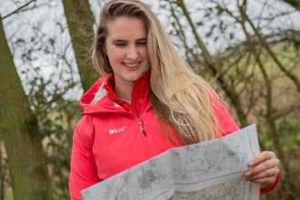 A young woman with long hair and a red coat reading a map