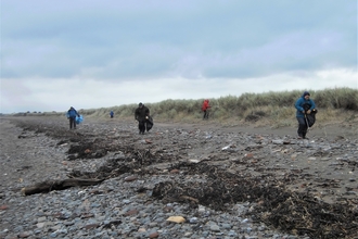 Four people take part in a litter-pick on a blustery beach