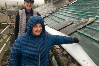 A man and a woman standing on scaffolding next to a roof