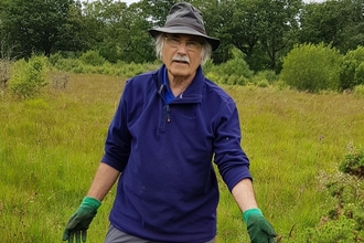A man in gardening gloves standing in a field