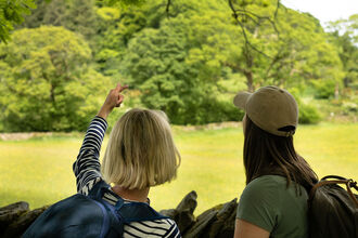 Two people looking across a field towards a woodland