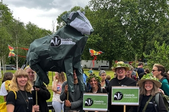 Image of people at rally holding up hand-made Cumbria Wildlife Trust badger 