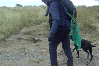 Large old tyre being removed from the beach