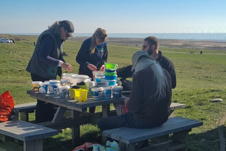 Four people gathered around a bench on the coast