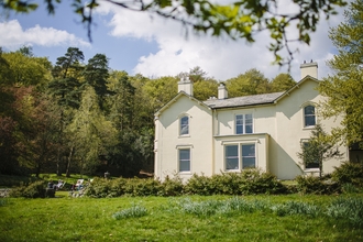 Photo shows a historic white house (Allan Bank) nestled in grass and trees.
