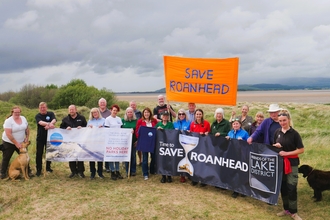 Group of people on beach with banners saying Save Roanhead