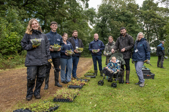 Group of people holding trays of plug plants and trowels