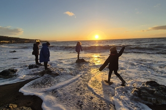 People at the shoreline in west cumbria at sunset