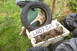 Lots of collected rubbish including tyres, number plate and a sink