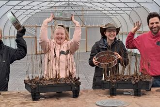 four people inside polytunnel with seedlings for Skiddaw Forest
