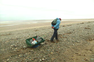 Volunteer dragging spoils from the beach
