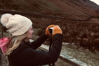 Girl outdoors in winter taking photo with camera 