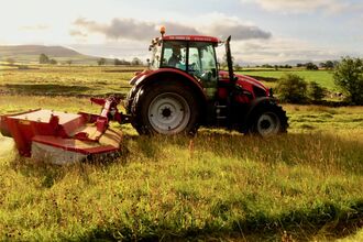 Tractor cutting meadow grass