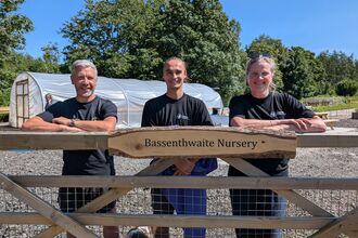 Three members of Cumbria  Wildlife Trust staff stand at new entrance to Bassenthwaite Nursery with polytunnel in background