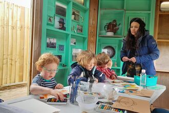 A table with pre-school children supervised by an adult. 
