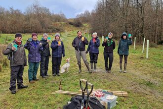 Group of people standing in countryside celebrating after planting shrubs