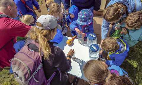 children at cold springs event filling jars containers with water