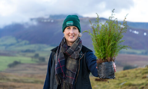 Woman holding up a tree ready to be planted at Eycott Hill Nature Reserve