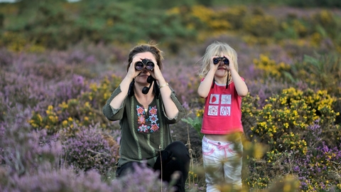 Mother and daughter spottingwildlife through binoculars