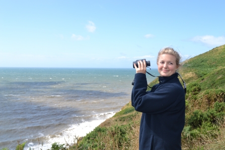 Image of Emily Baxter sea watching with binoculars at St Bees
