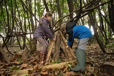 Image of boy and girl building den in woods © Adrian Clarke