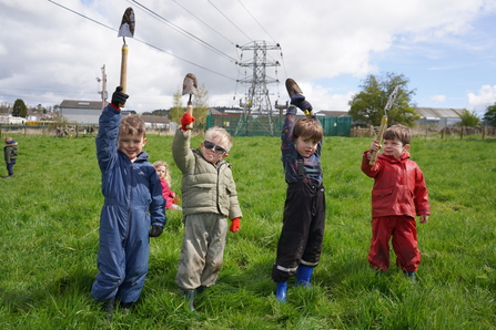 Image of four young children holding up small spaces in a field