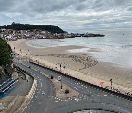 Scarborough beach with sand art of a cetacean tail fin