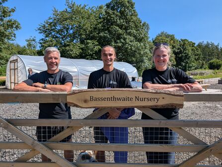 Three members of Cumbria  Wildlife Trust staff stand at new entrance to Bassenthwaite Nursery with polytunnel in background