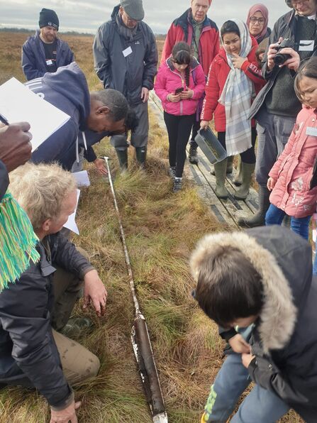 Group of people looking at a peat bog sample