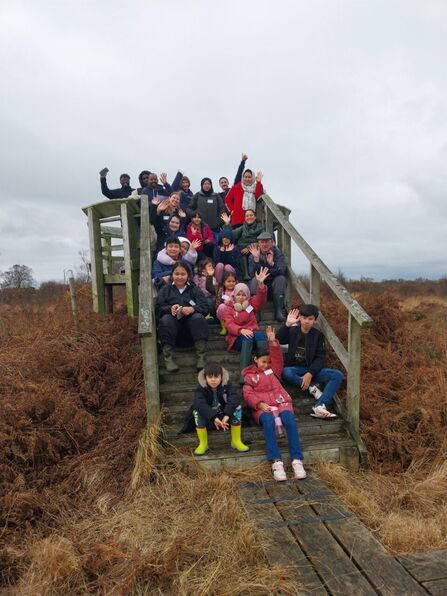 Group of people sittng on a boardwalk lookout at Drumburgh Moss nature reserve