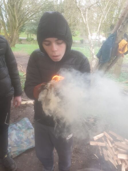 young person making fire from sticks during forest school