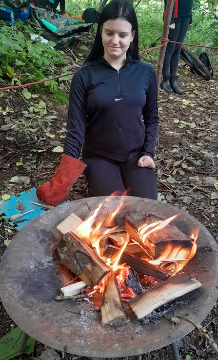 young person making a fire in a fire pit at a forest school