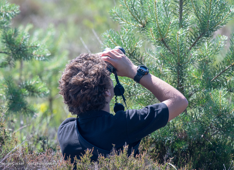 image of young conservationist, Andy Macaulay using binoculars out in the field