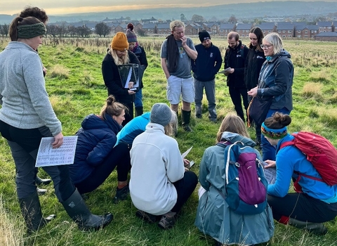 A community group gathered outdoors on grassland with Cumbria Wildlife Trust outside a town
