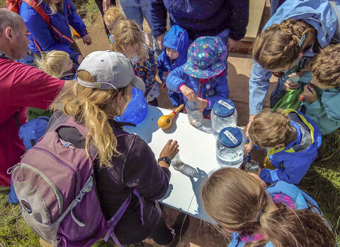children at cold springs event filling jars containers with water
